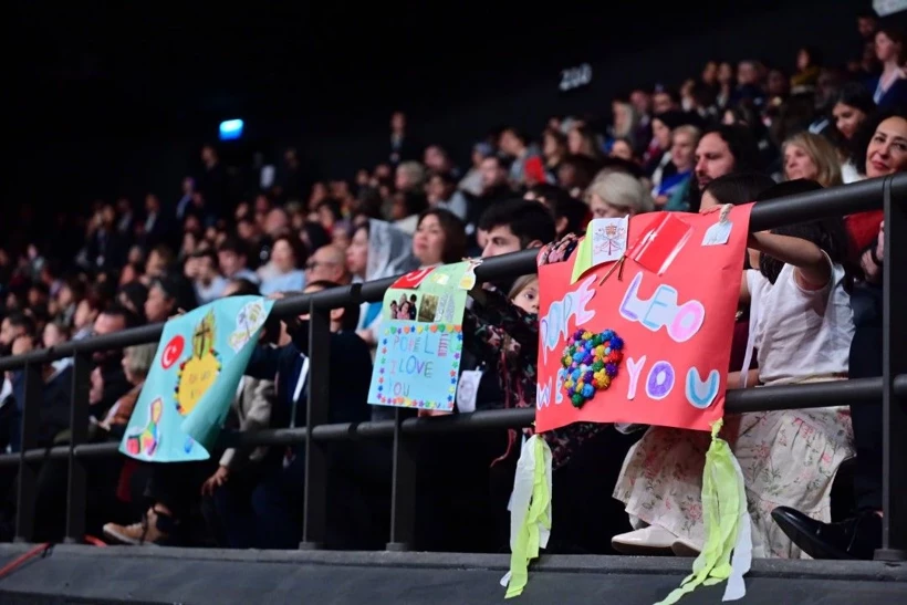 Children holding colorful welcome signs for Pope Leo XIV at Volkswagen Arena in Istanbul.